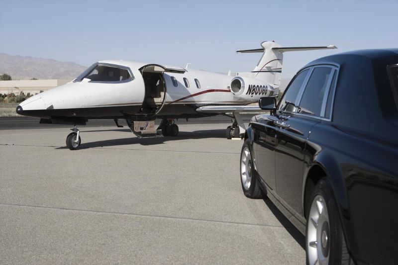 Black limo parked by white private plane