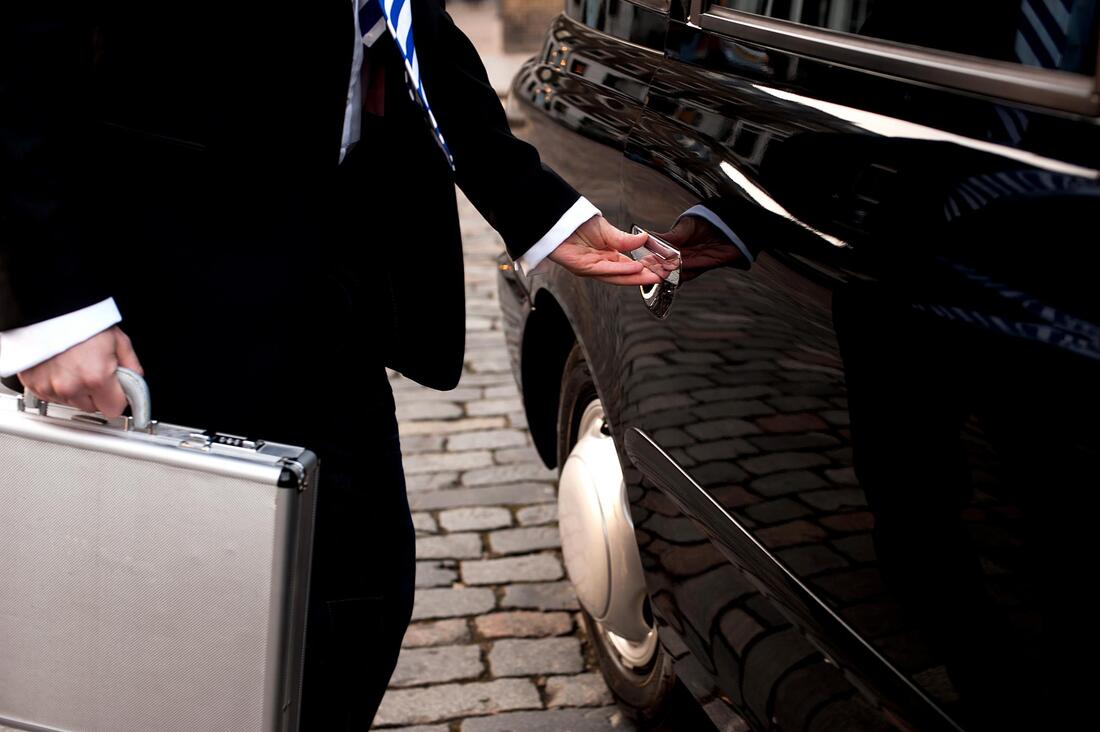 Chauffeur opening door of car at airport